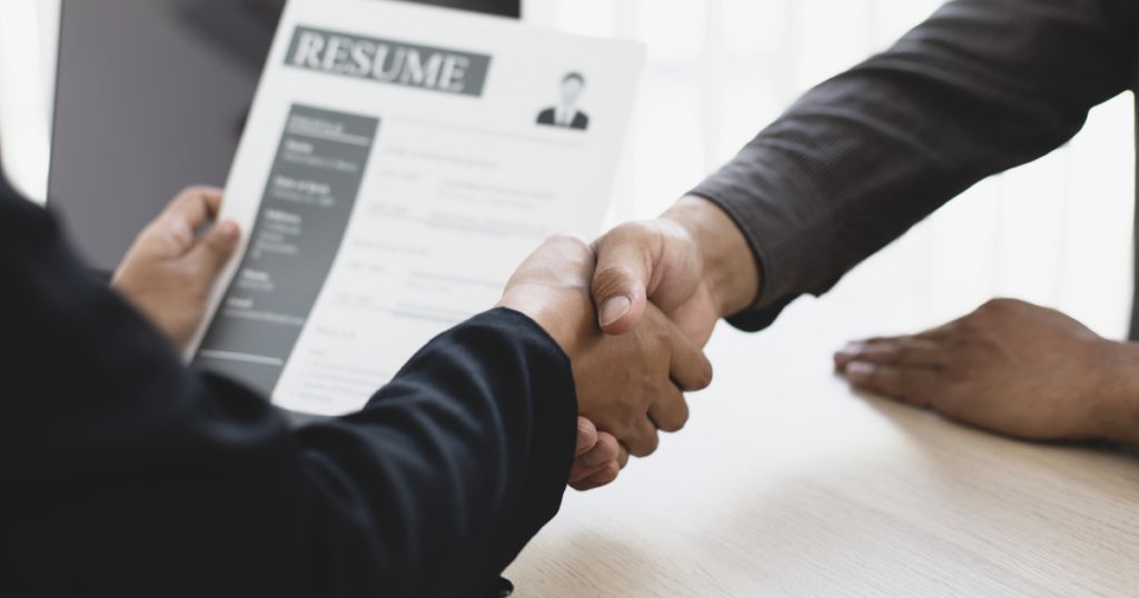 a man holding a resume while shaking the hand of another man