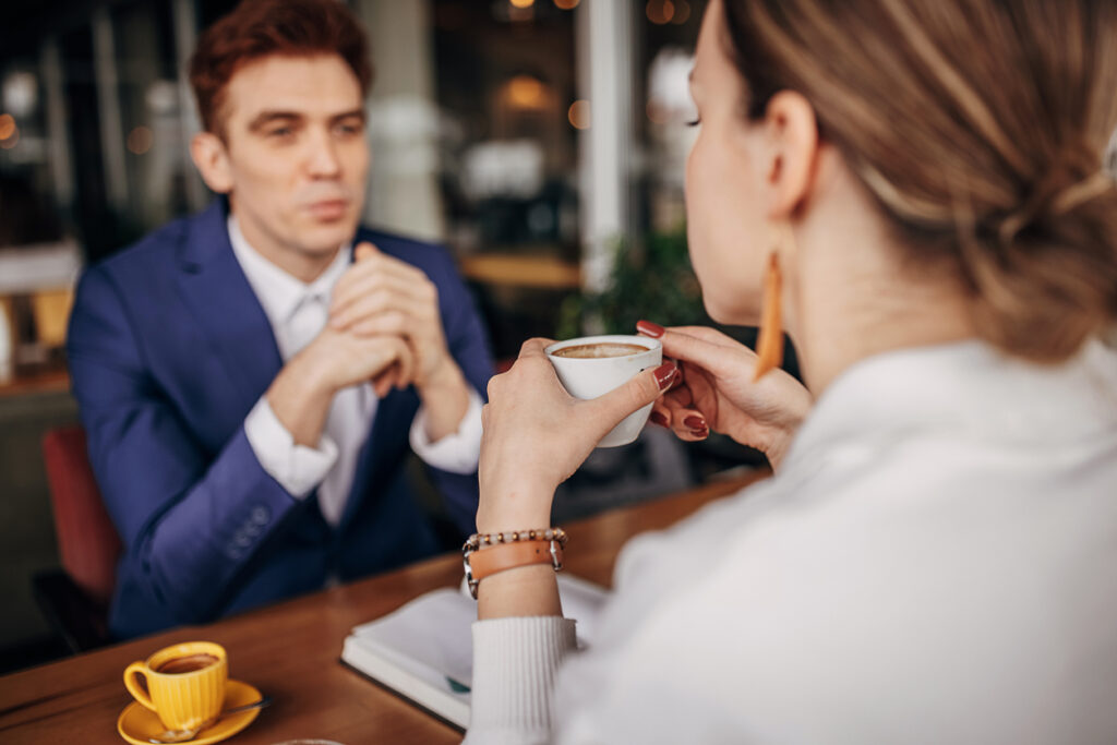 Young businessman having a coffee interview with a woman in cafe.