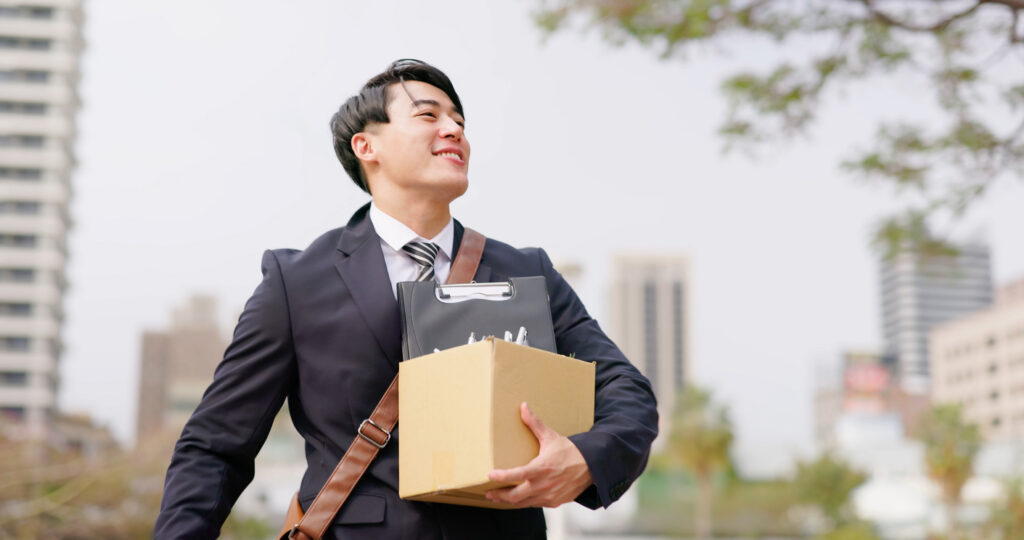 asian happy businessman on his way for his first day in his job and walk in city with box