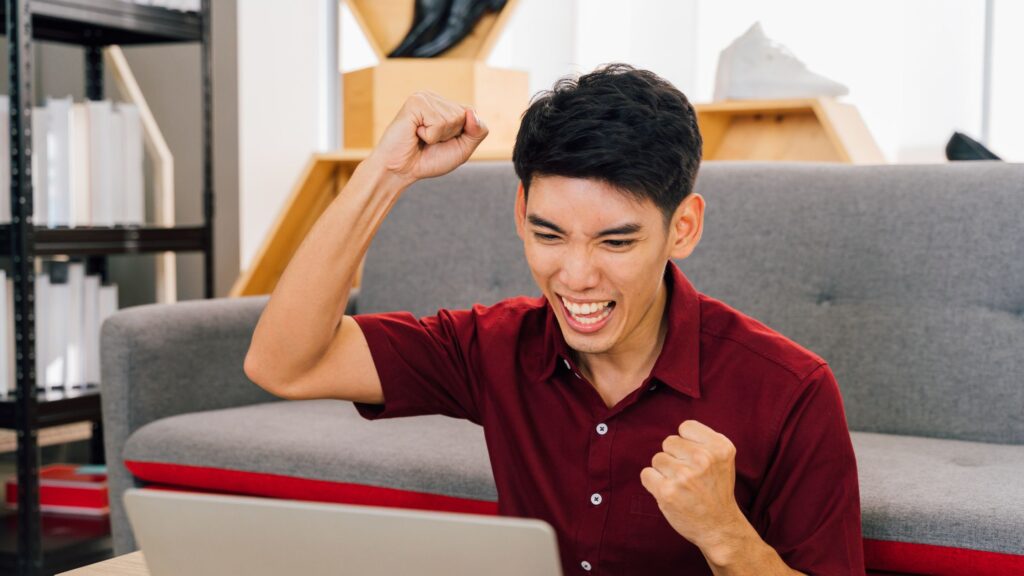 a happy man wearing a red polo in front of a laptop