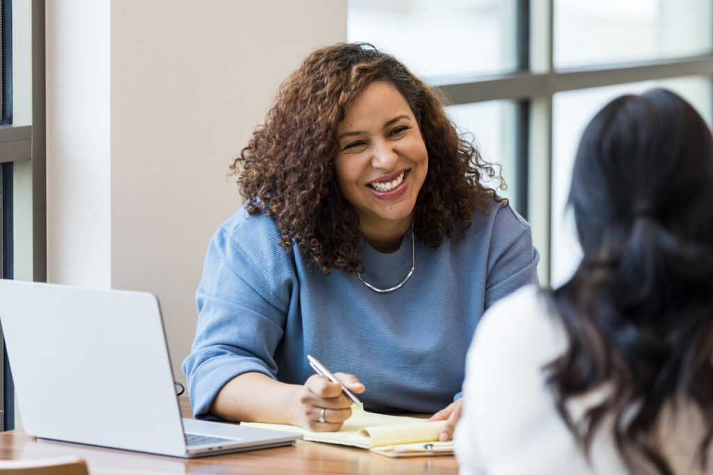 The mature adult female business owner smiles encouragingly at a female job applicant.