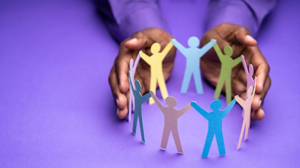 hands holding paper cut outs of people holding hands to depict diversity and inclusion in remote work