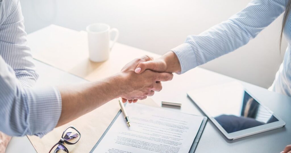 two people shaking hands after signing a contract