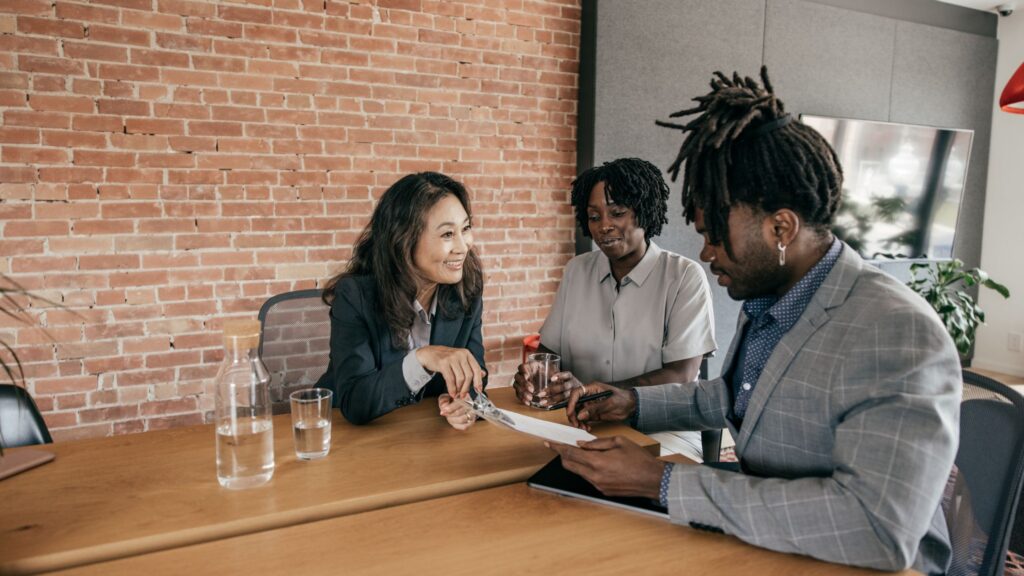 a black man reviewing a document with an asian woman and another black woman