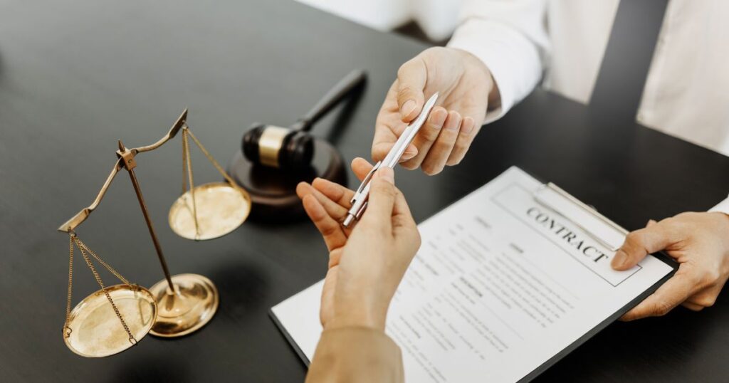 a man handing a woman a pen for signing a contract as part of remote employment laws