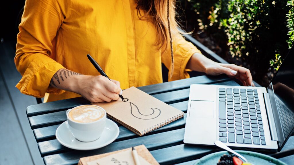 a woman working remotely and drawing a question mark in a notebook