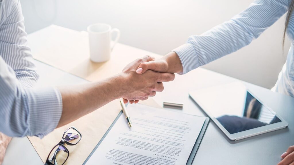 two people shaking hands after drafting remote temporary and contractual work agreements