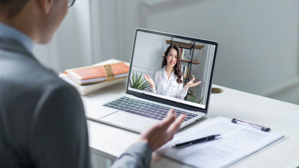 a man interviewing a woman through a laptop to depict remote work and unconscious bias