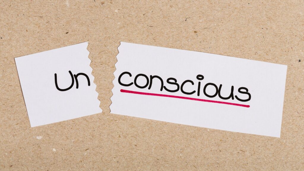 the word "unconscious" written on a piece of paper that is torn to form the words un and conscious